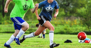 man and woman chase after soccer ball regulated equipment for soccer ball